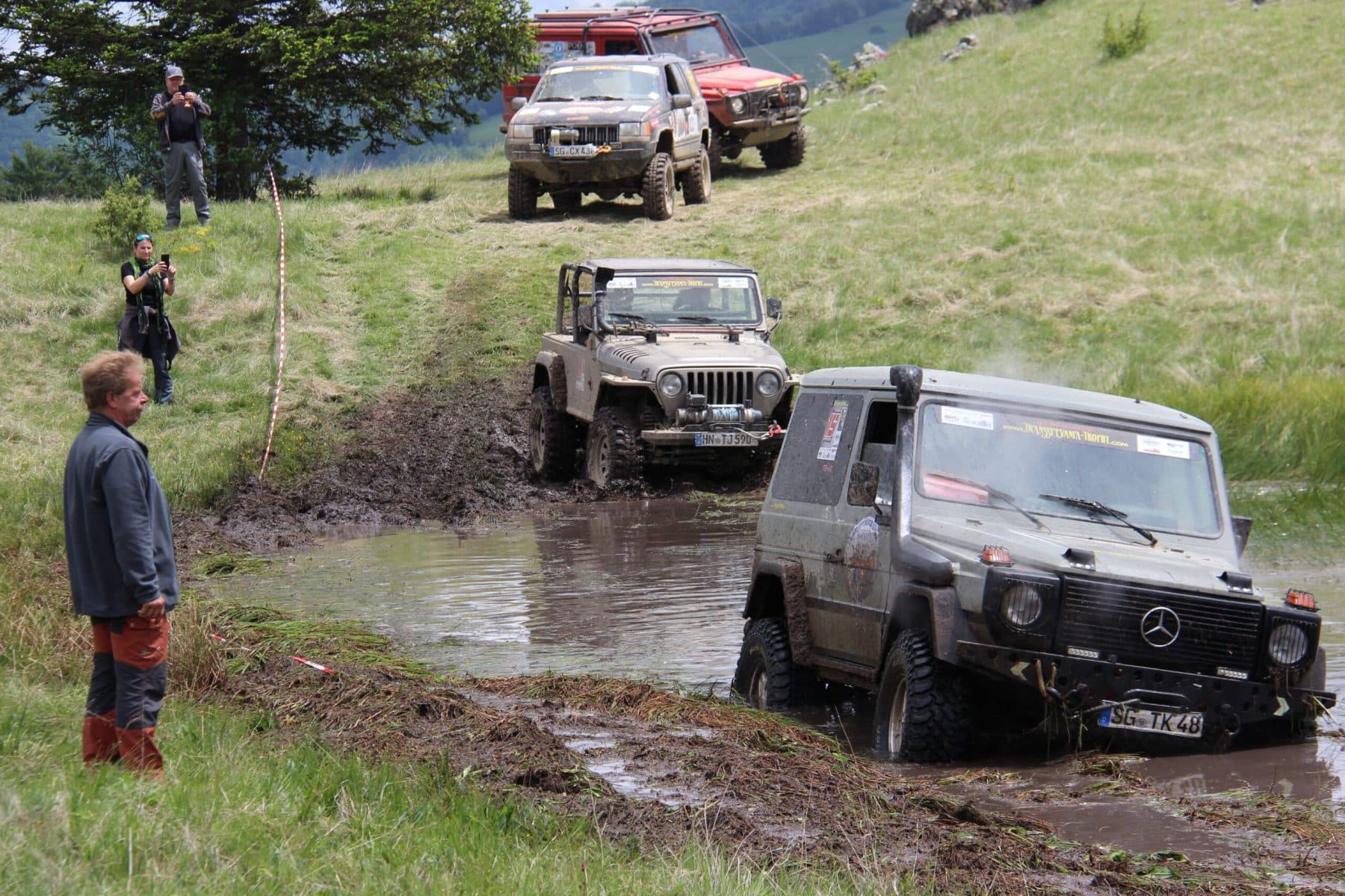 Several Trophy vehicles crossing a deep mud hole together